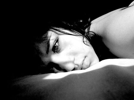 Chica tumbada en la cama cara de sufrir depresion